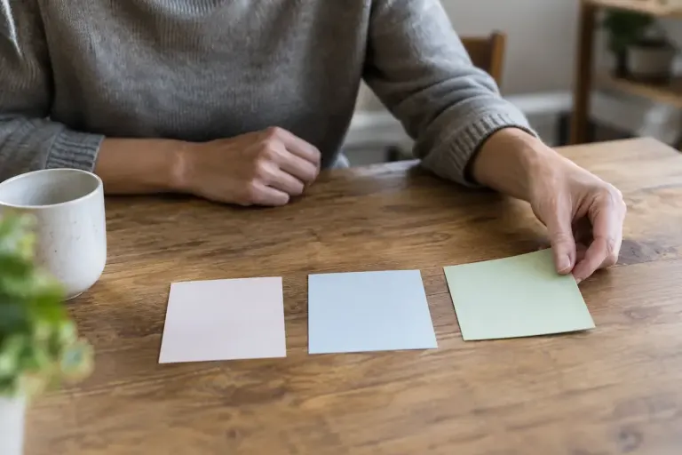 Person adding a third option card beside two choices on a table.